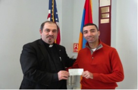 Rev. Fr. Mesrob Lakissian accepts a check of $2,000 from Raffi Hovsepian of the New York Armenian Students Association, for Syrian Armenian relief. The money was raised at a Thanksgiving party of five youth organizations in the NY metro area.